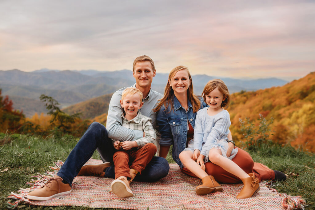 Family sits together and smiles at the camera during Fall Family Pictures on the Blue Ridge Parkway in Asheville, NC.