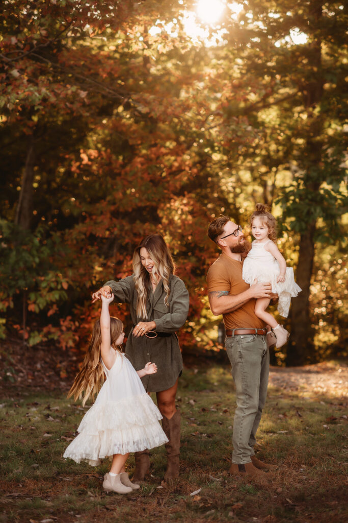 Parents play with their children in the sunshine during Fall Mini Sessions in Asheville, NC.