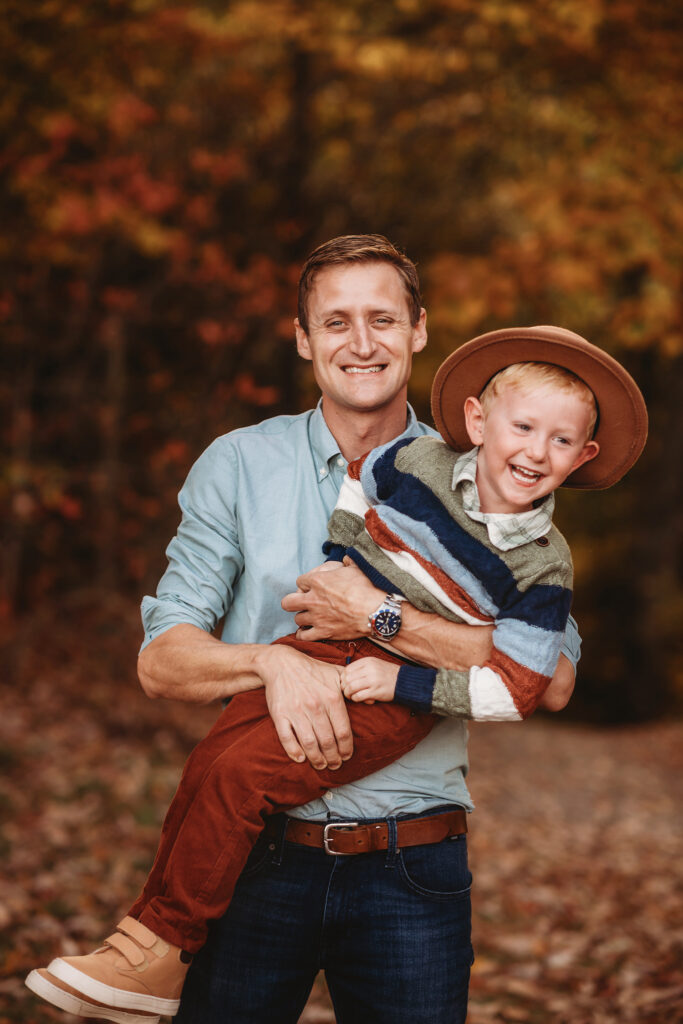 Father holds his son during Fall Family Photos on the Blue Ridge Parkway in Asheville, NC.