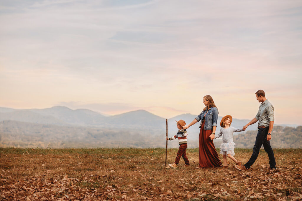 Family walks across a mountain top during a Fall Family Photoshoot on the Blue Ridge Parkway in Asheville, NC.