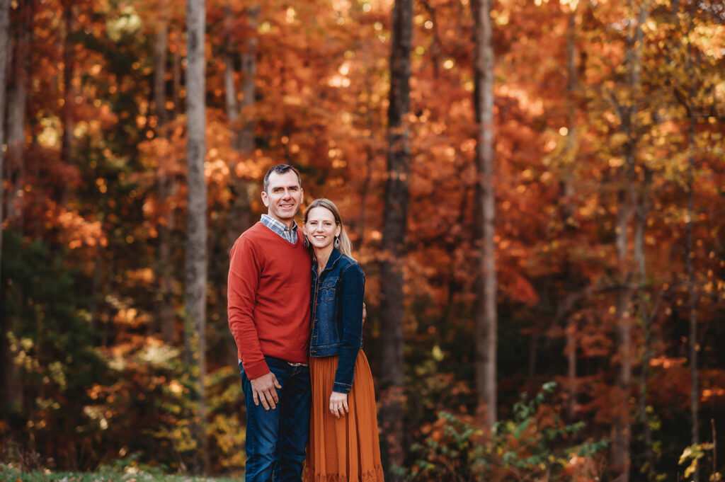 Couple poses together for Fall Family Portraits at Biltmore Estate in Asheville, NC after learning about the Best Places to See Fall Color in Asheville.