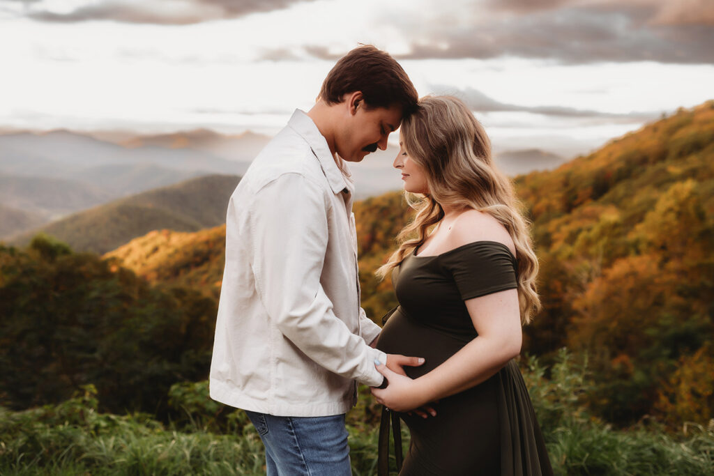 Expectant parents pose for Maternity Portraits in the fall, on the Blue Ridge Parkway with Asheville Portrait Company after Planning a Babymoon in Asheville, NC.