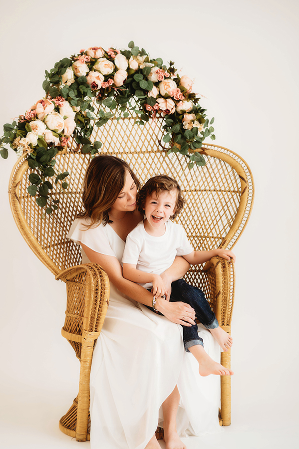 Mother poses with her son for a simple, all white studio photoshoot in Asheville, NC portrait studio.