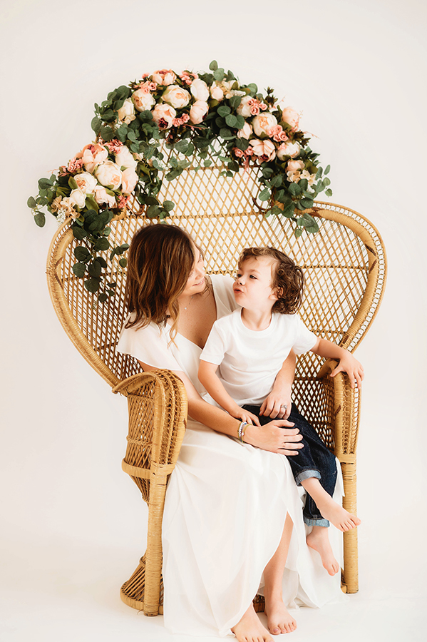 Mother poses with her son for a simple, all white studio photoshoot in Asheville, NC portrait studio.