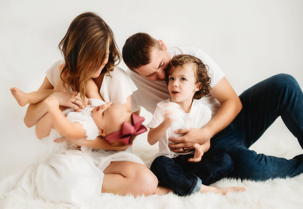 Young family poses for a simple, all white studio photoshoot in Asheville, NC portrait studio.