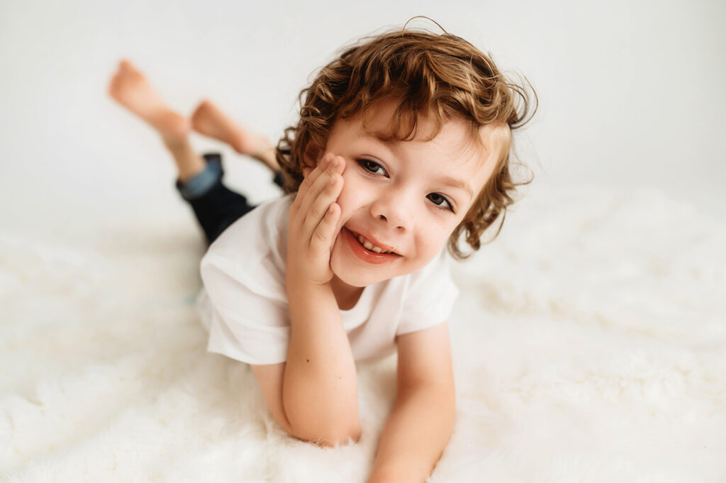 Little boy poses for a simple, all white studio photoshoot in Asheville, NC portrait studio.