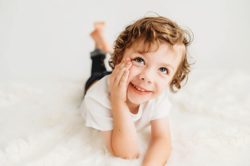 Little boy poses for a simple, all white studio photoshoot in Asheville, NC portrait studio.
