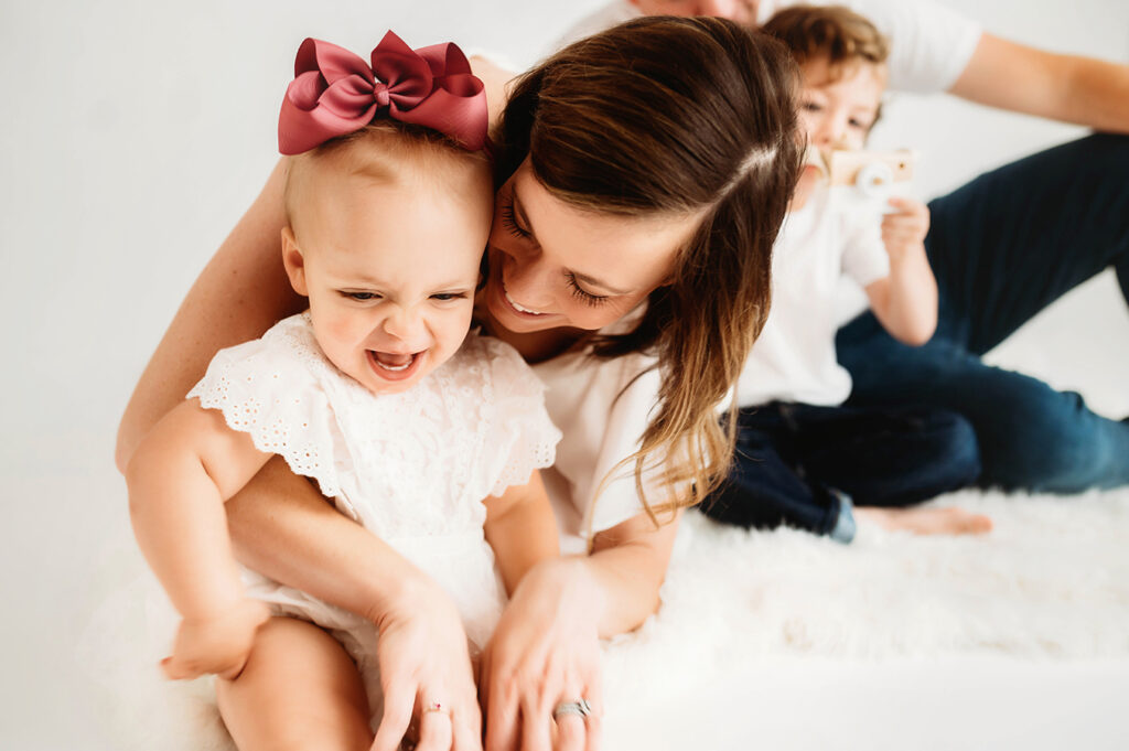 Young family poses for a simple, all white studio photoshoot in Asheville, NC portrait studio.
