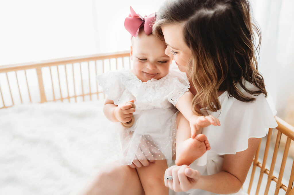 Mother poses with her daughter for a simple, all white studio photoshoot in Asheville, NC portrait studio.