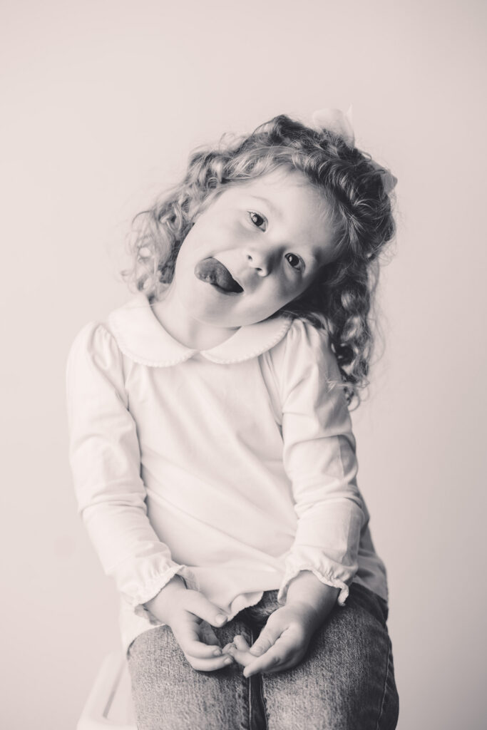 Little girl makes silly faces at the camera during Asheville Personality Portrait Pop-Up.