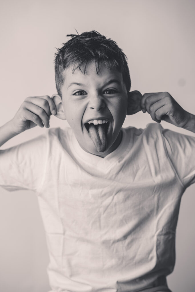 Child makes silly face at the camera during Personality Portrait Session in Asheville, NC.