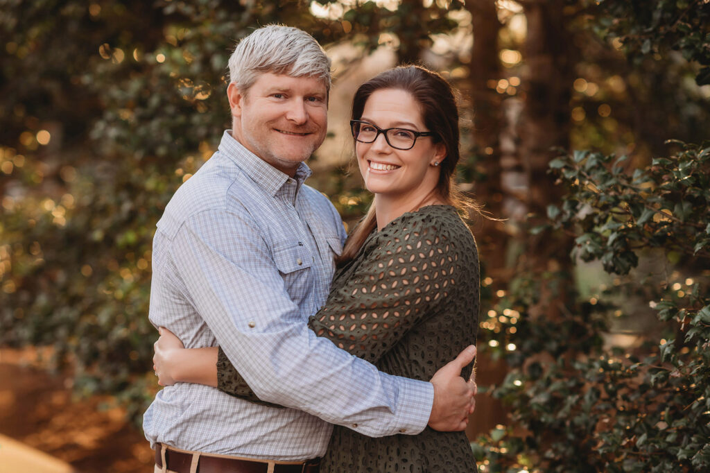 Couple embraces each other for portraits during Multi-Generational Family Photoshoot at the NC Arboretum in Asheville, NC. 