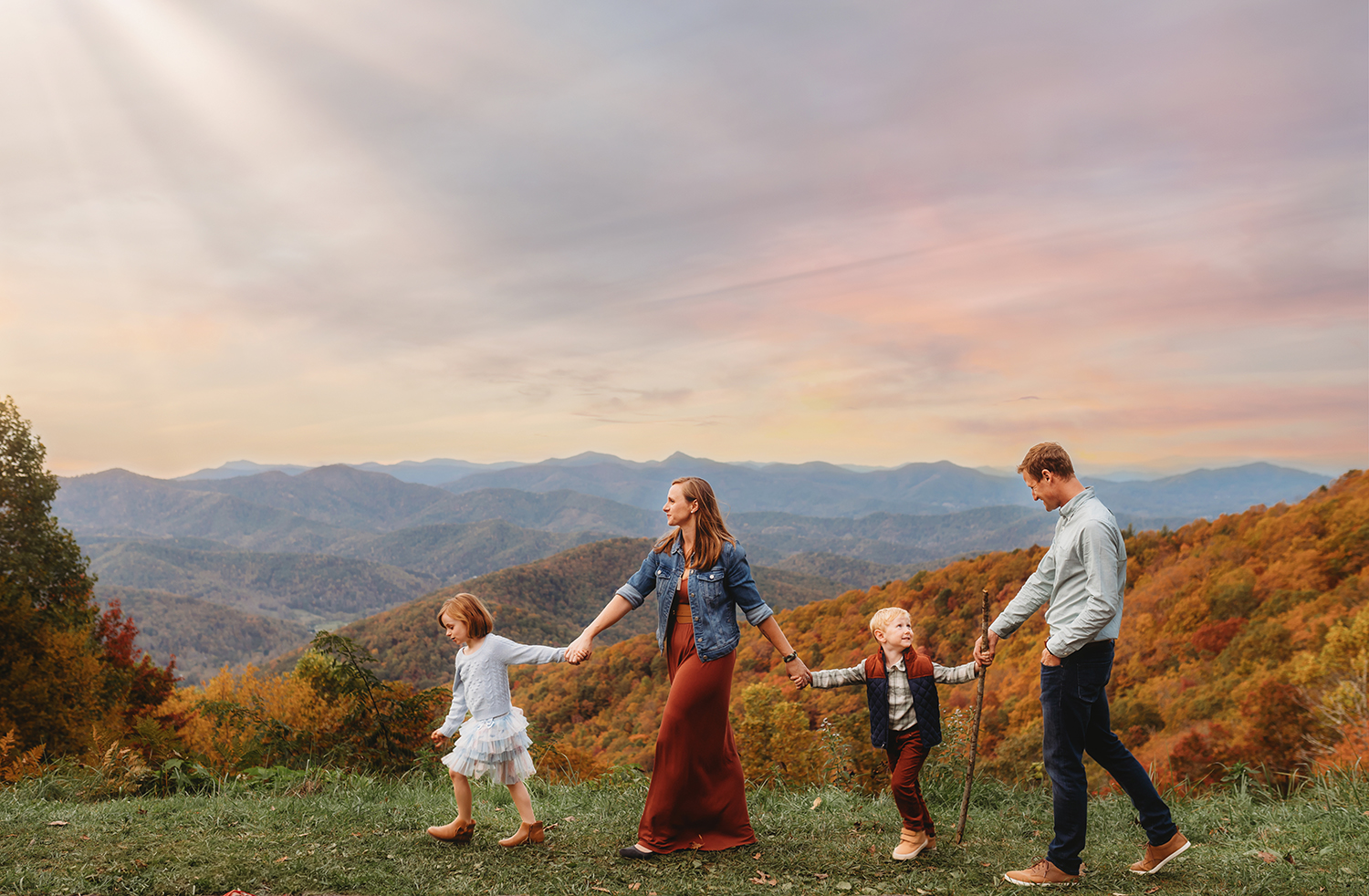 Family walks across a mountain top during a Fall Family Photoshoot on the Blue Ridge Parkway in Asheville, NC.
