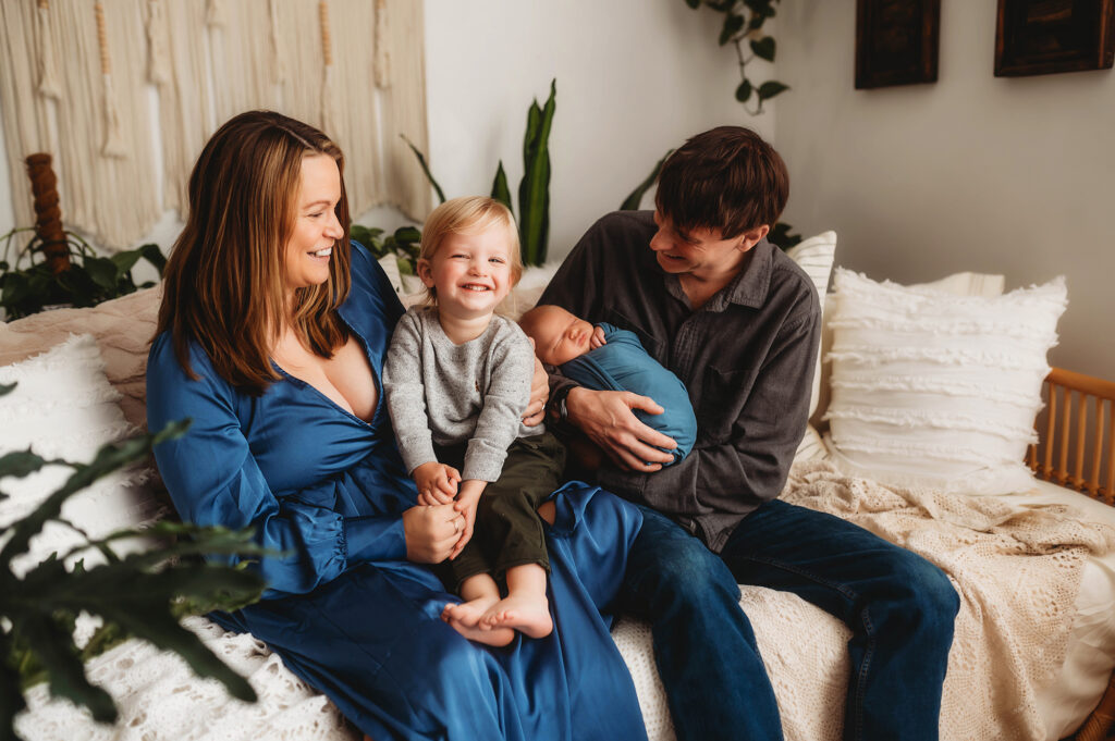 New parents embrace their toddler and newborn baby during Newborn Photoshoot in Asheville, NC. 