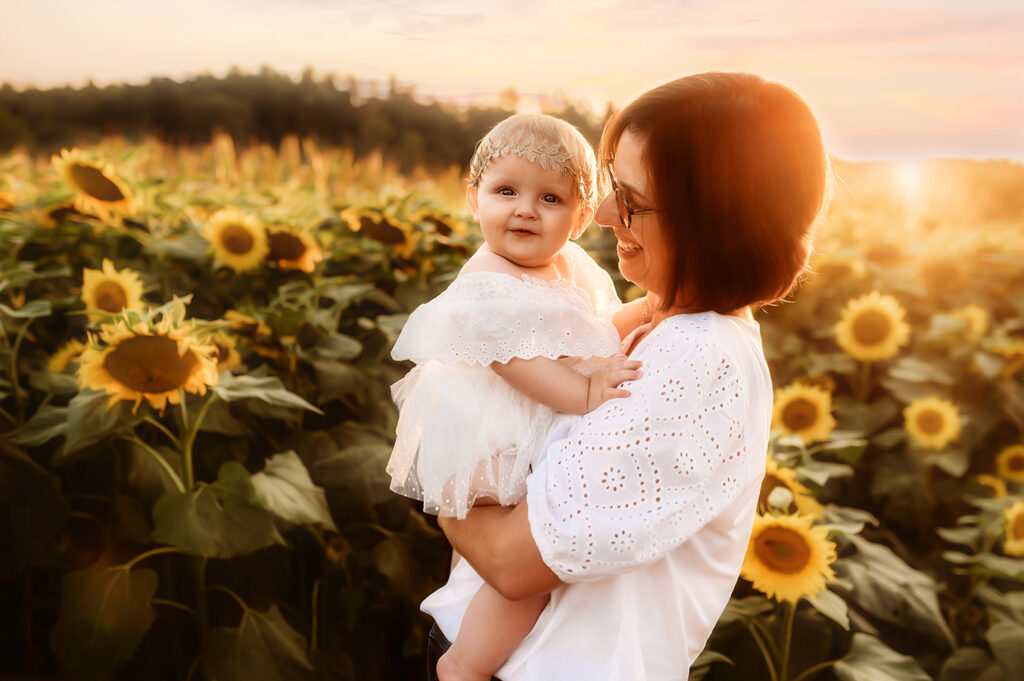 Mother plays with her baby during a Sunflower Field Portrait Session at Biltmore Estate in Asheville, NC.