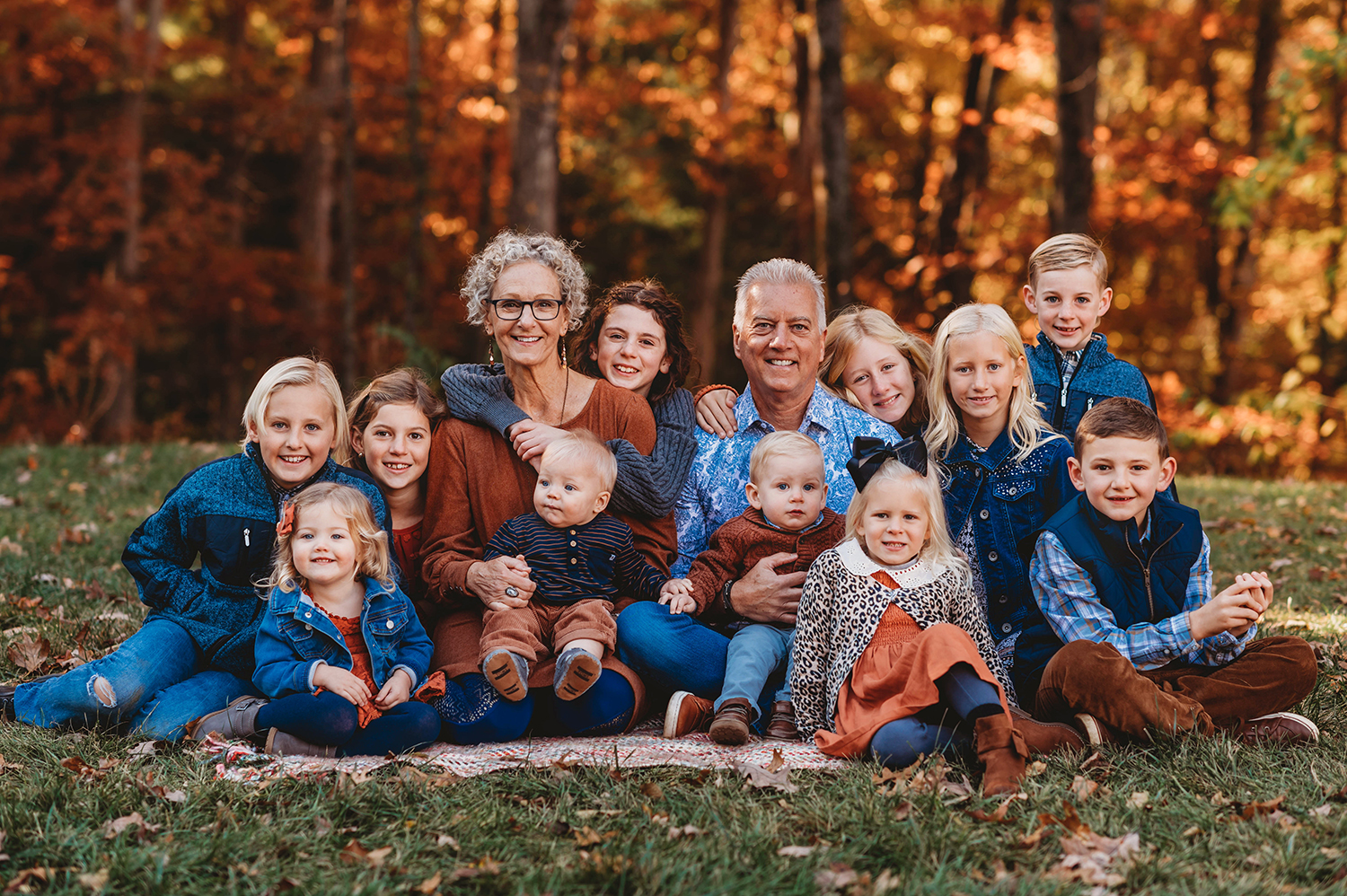Grandparents sit surrounded by their 14 grandchildren during a Fall Family Portrait Session in Asheville, NC during their extended family vacation.