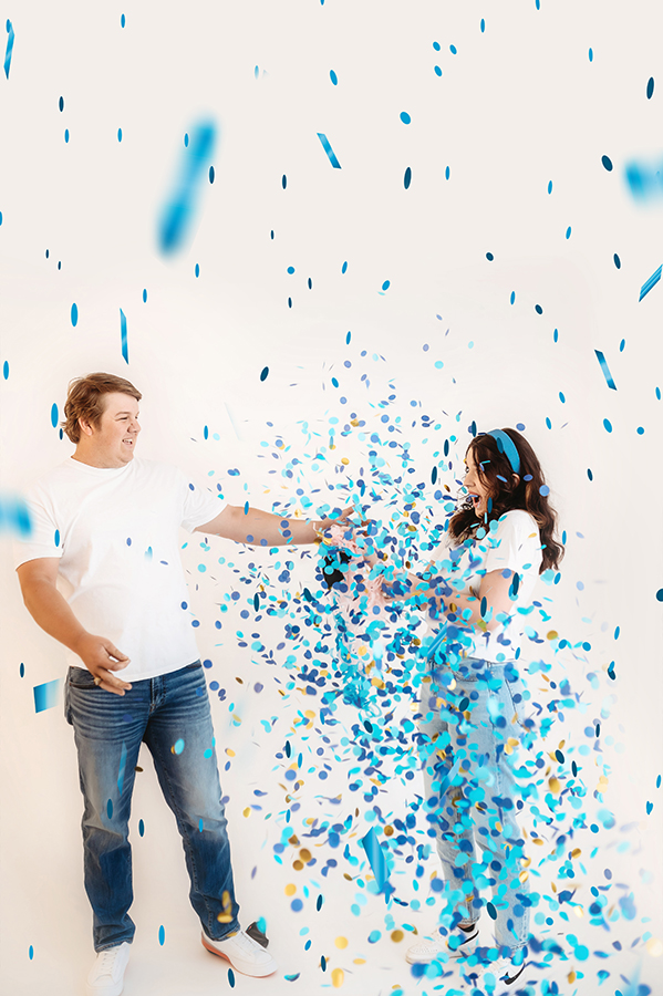 Couple pops balloon with blue confetti for Gender Reveal Photoshoot in Asheville, NC.