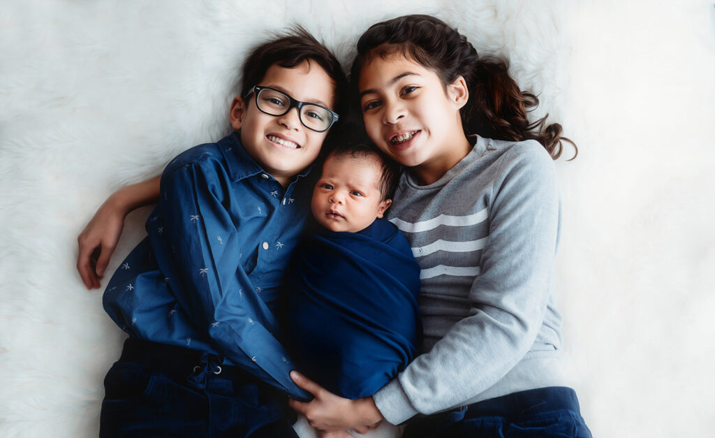 Newborn Baby posed with his Siblings for Newborn Portrait Session at Asheville, NC Newborn Photography Studio.