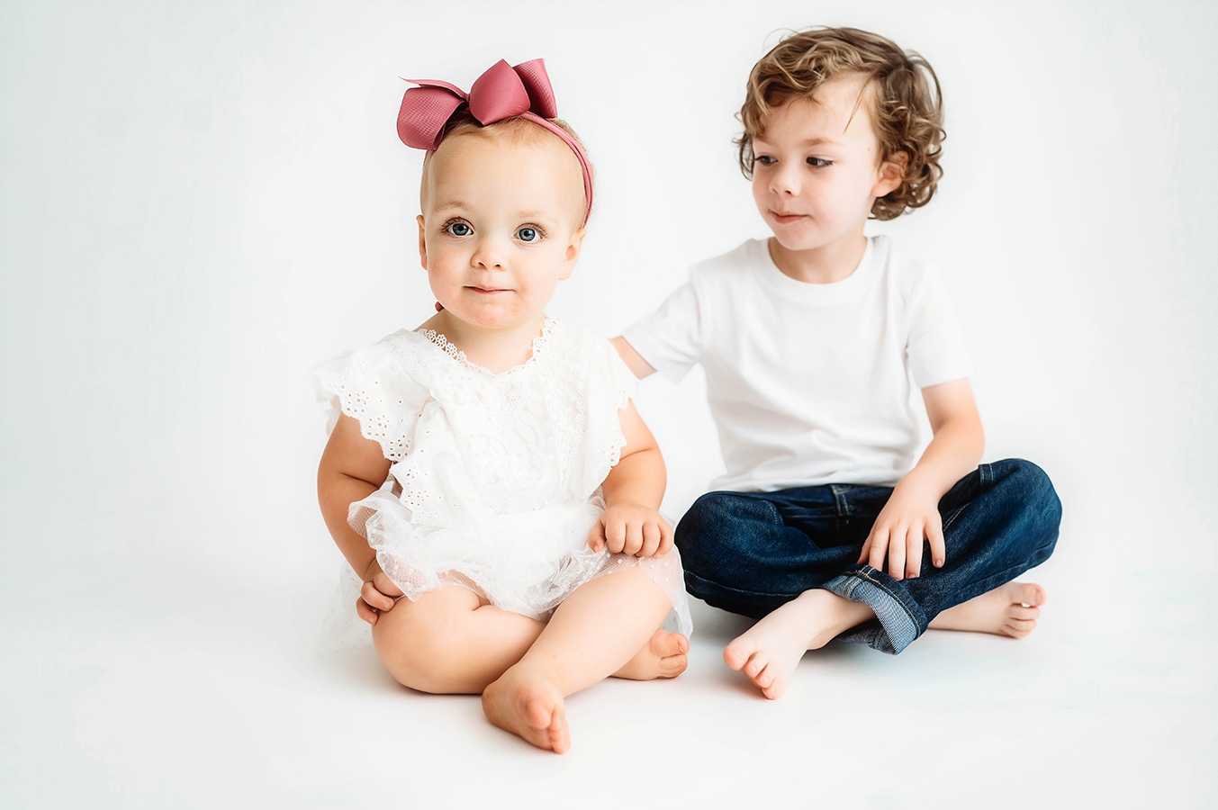Siblings pose for a simple, all white studio photoshoot in Asheville, NC portrait studio.