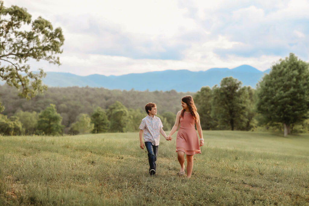Siblings walk through a field togethr during Family Photoshoot at Biltmore Estate in Asheville, NC. 