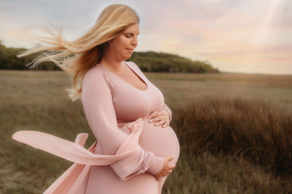 Pregnant mother embraces her baby bump during Maternity Photoshoot in Asheville, NC after receiving fertility treatment from the Best Fertility Specialists in Asheville. 