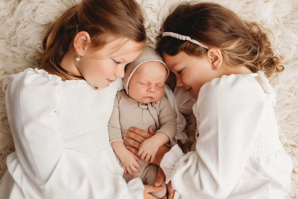 Asheville Newborn Photography Studio provides the Best Newborn Photos in Asheville. Portrait of a Siblings holding their Newborn Baby brother during his Infant Photoshoot in Asheville.
