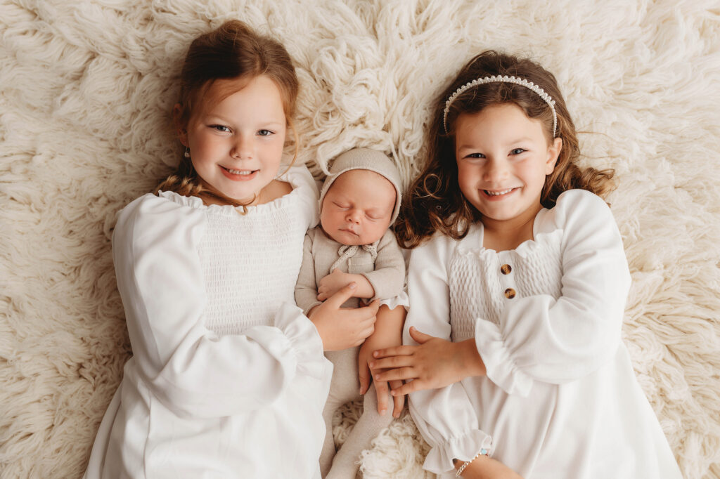 Asheville Newborn Photography Studio provides the Best Newborn Photos in Asheville. Portrait of a Siblings holding their Newborn Baby brother during his Infant Photoshoot in Asheville.
