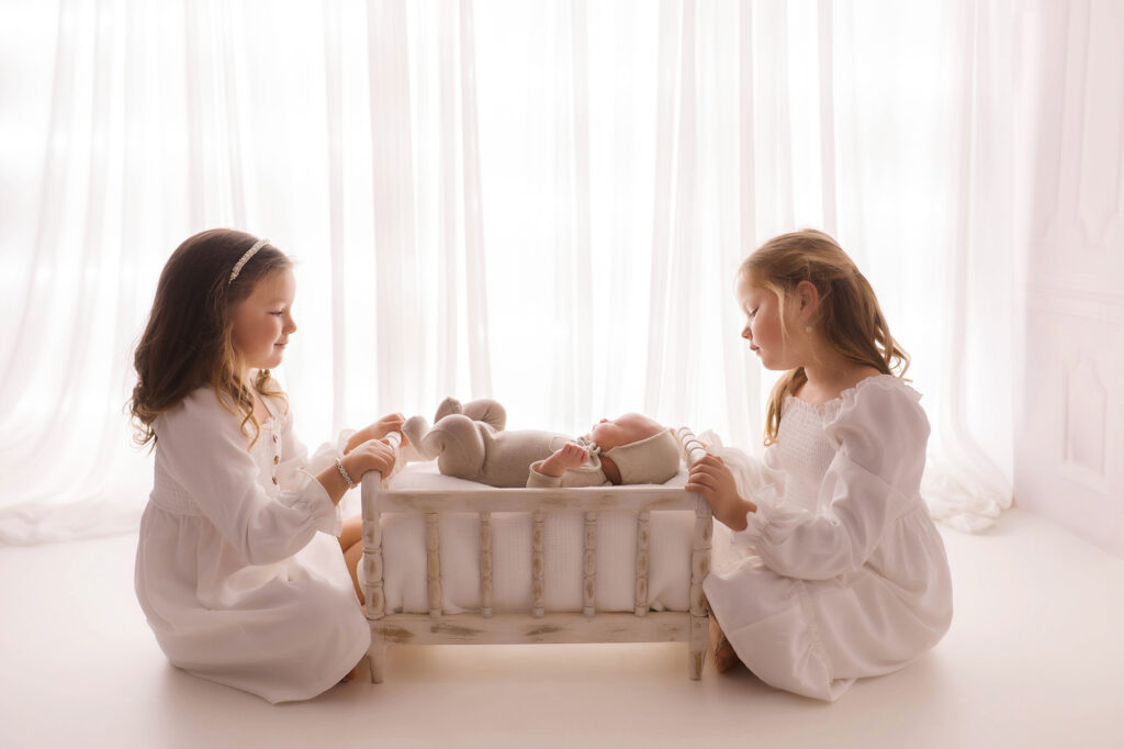 Asheville Newborn Photography Studio provides the Best Newborn Photos in Asheville. Portrait of a Siblings holding their Newborn Baby brother during his Infant Photoshoot in Asheville.