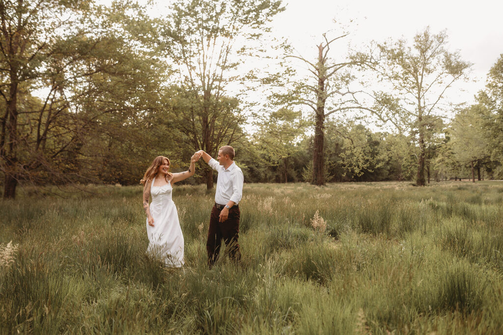 Newly Engaged Couple playfully dances in a field at Biltmore Estate during their Engagement Photos with Asheville Portrait Company in Asheville, NC