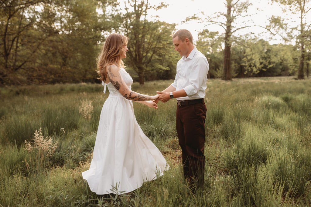 Newly Engaged Couple playfully dances in a field at Biltmore Estate during their Engagement Photos with Asheville Portrait Company in Asheville, NC