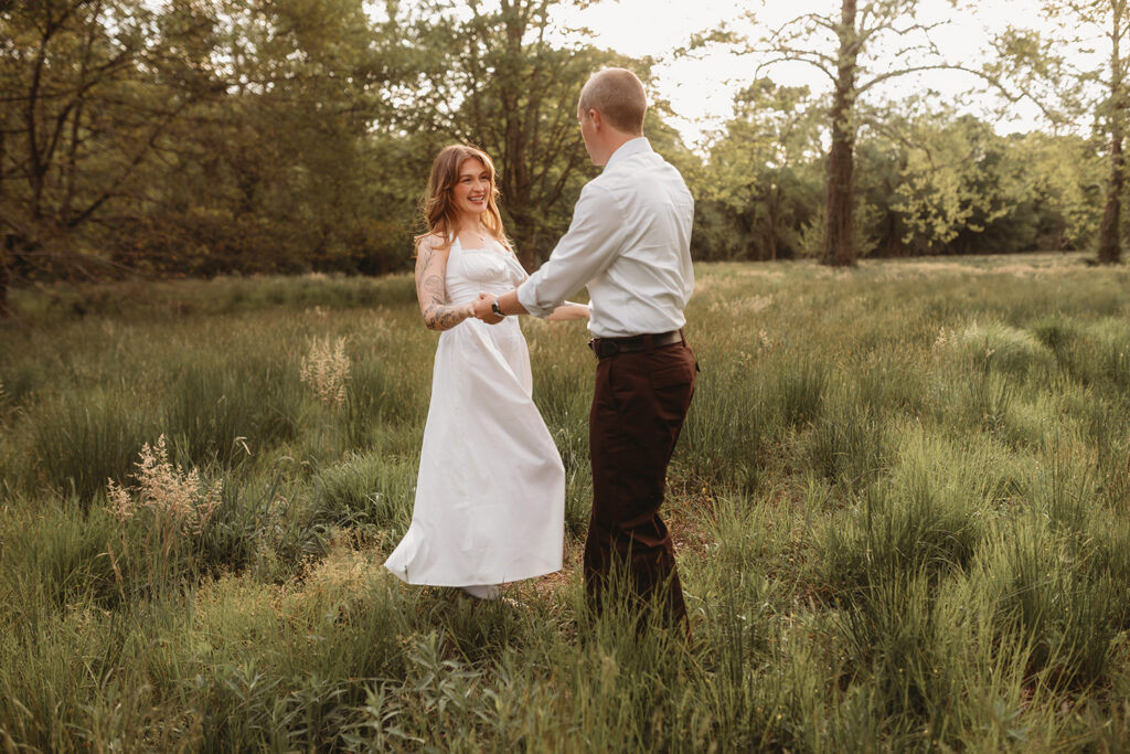 Newly Engaged Couple playfully dances in a field at Biltmore Estate during their Engagement Photos with Asheville Portrait Company in Asheville, NC