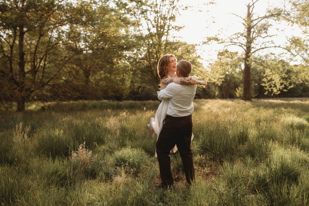 Newly Engaged Couple playfully dances in a field at Biltmore Estate during their Engagement Photos with Asheville Portrait Company in Asheville, NC