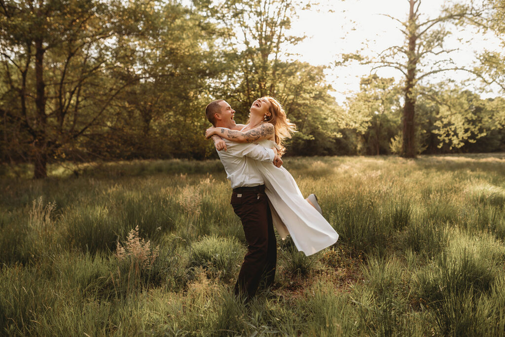 Newly Engaged Couple playfully dances in a field at Biltmore Estate during their Engagement Photos with Asheville Portrait Company in Asheville, NC