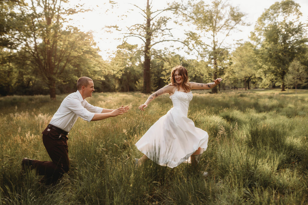 Newly Engaged Couple chases each other through field at Biltmore Estate during their Engagement Photos with Asheville Portrait Company in Asheville, NC