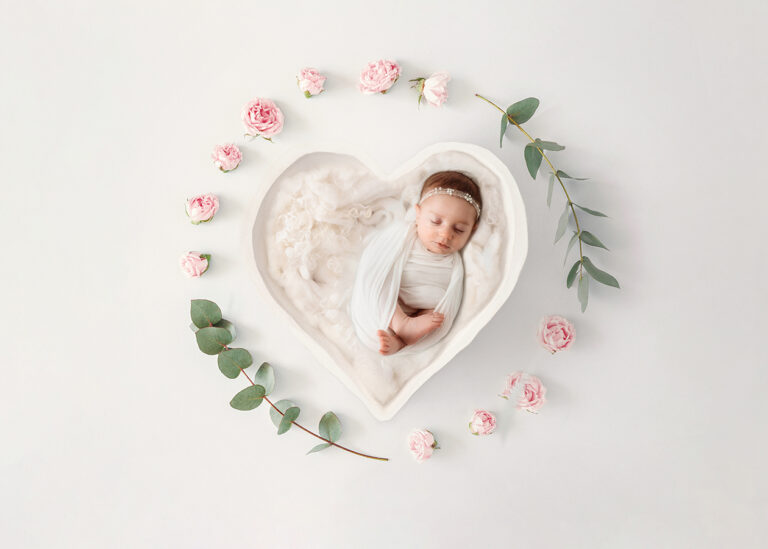 Newborn Baby posed in a heart bowl with pink and white florals during Newborn Portrait Session in Asheville, NC.
