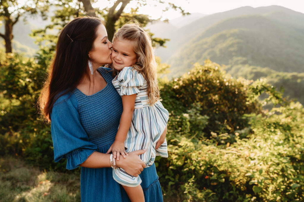 Mother kisses her daughter during a Family Photoshoot on the Blue Ridge Parkway in Asheville, NC. 