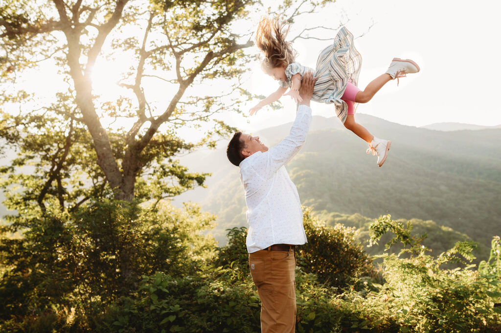 Father tosses his daughter in the air during Family Photos on the Blue Ridge Parkway in Asheville, NC. 